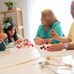 Grandparents and grandchildren engage in a creative building activity indoors.