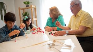 Grandparents and grandchildren engage in a creative building activity indoors.