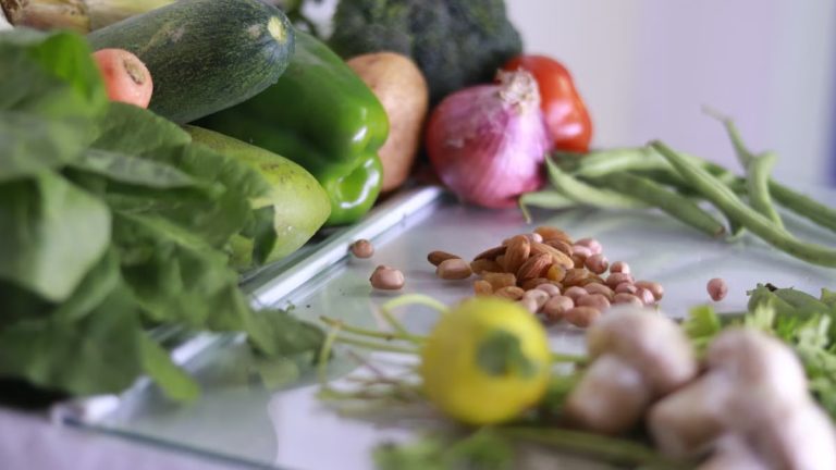 From above of various fresh organic colorful vegetables and nuts placed on glass tabletop in light kitchen
